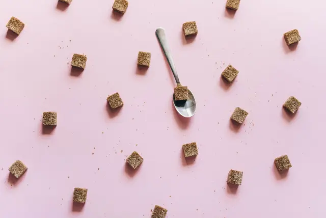 Brown sugar cubes scattered across a plain coloured surface, seen from above.