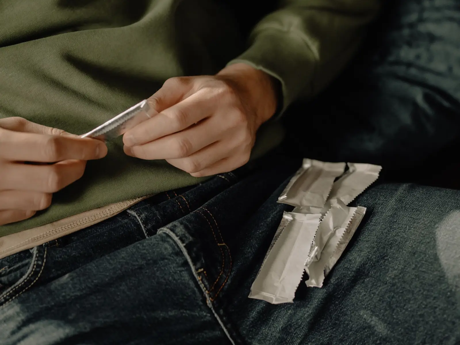 A person unwrapping a stick of chewing gum at home.