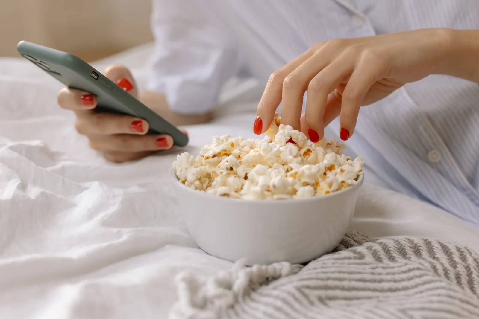 A close-up of a hand holding a phone at a table while eating.