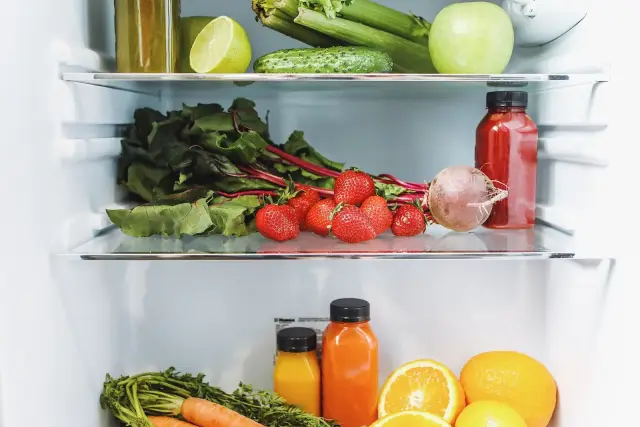A woman looking into an open refrigerator in a modern kitchen.