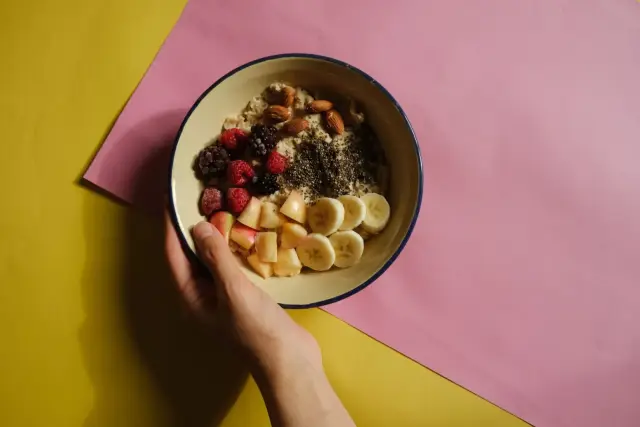 An oatmeal bowl topped with fresh fruit and nuts.