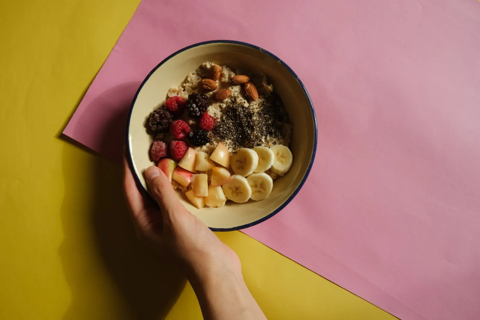 An oatmeal bowl topped with fresh fruit and nuts.