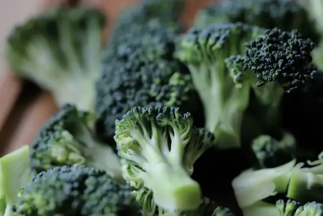 Fresh green broccoli florets on a board.