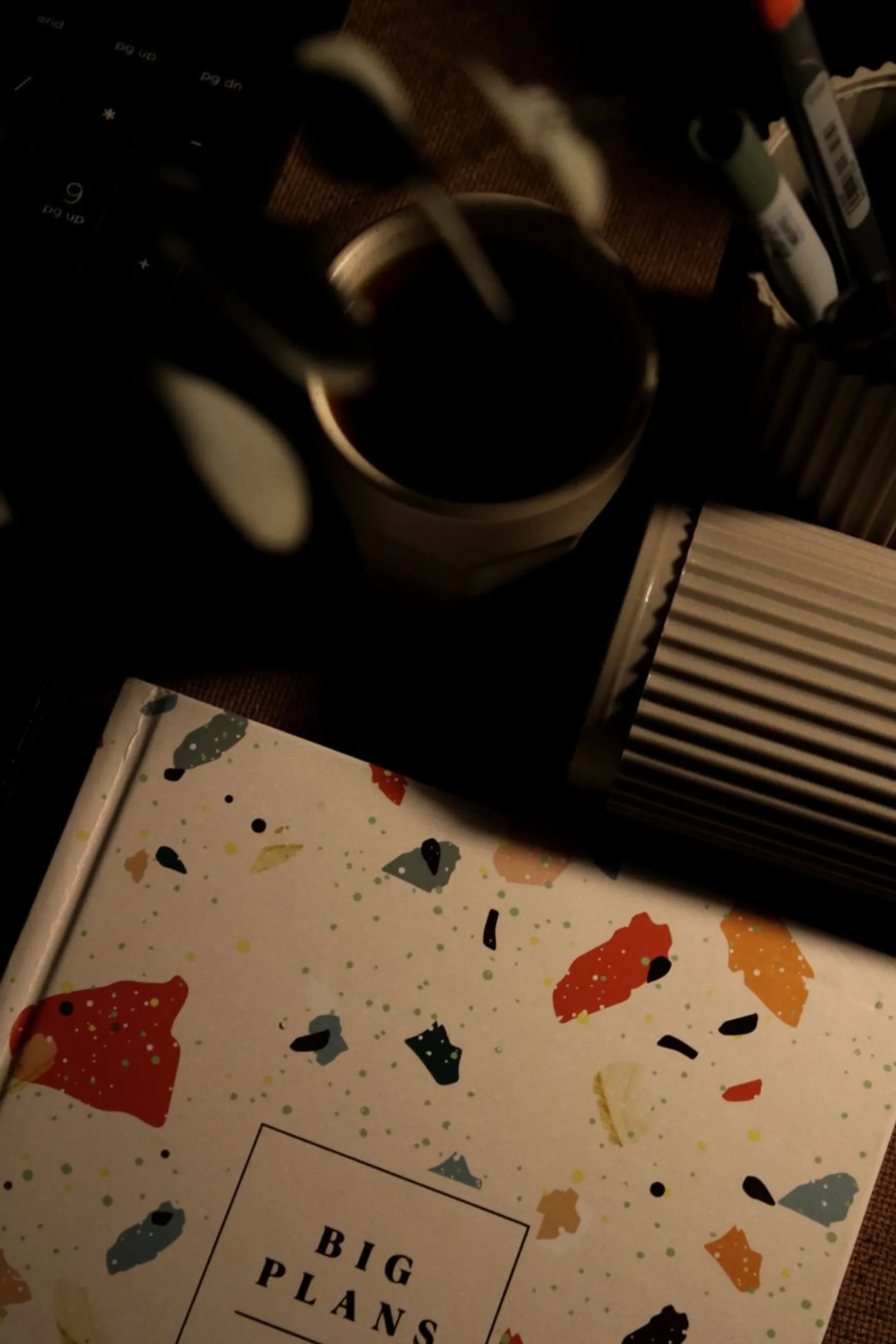 An open notebook beside a coffee mug on a home desk in warm morning light.