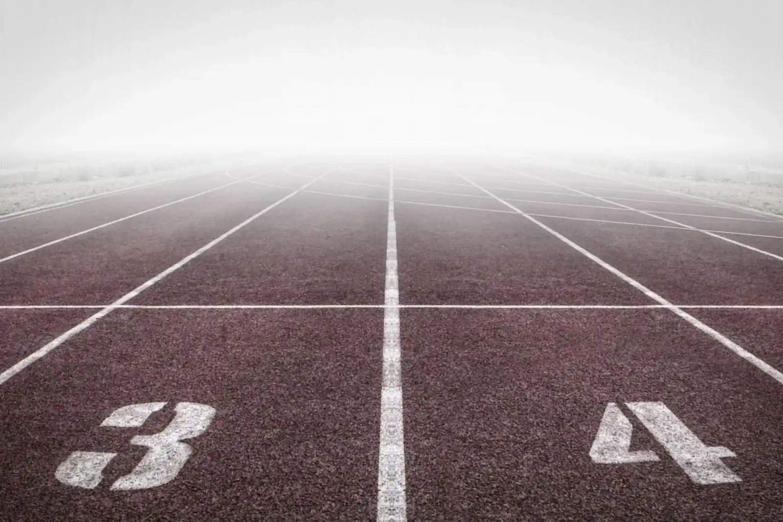 A fit woman tying her running shoes on an outdoor track, ready to move.