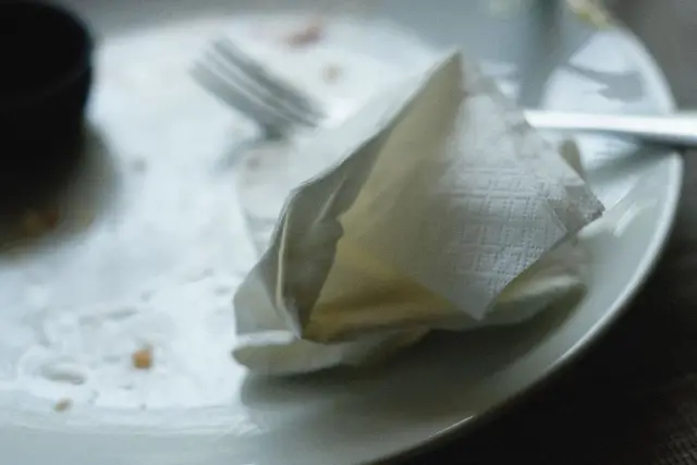 An empty plate and fork on a plain table.