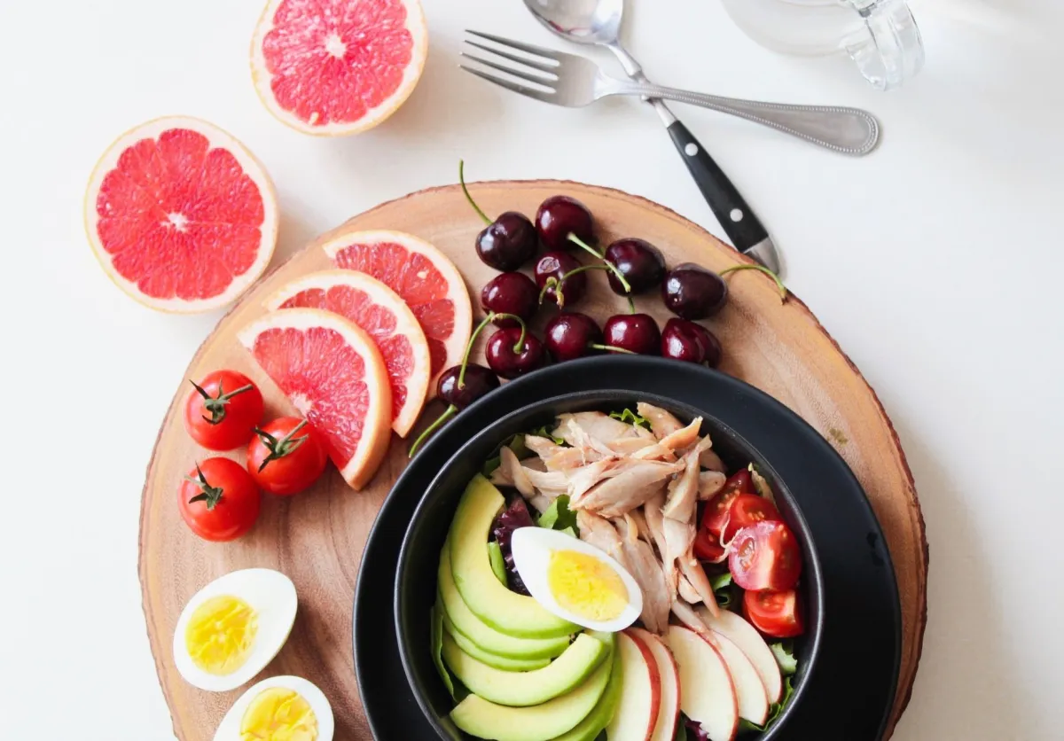 A vibrant plate of eggs, avocado, fruit, tomatoes, and lean protein, a protein-forward maintenance meal.