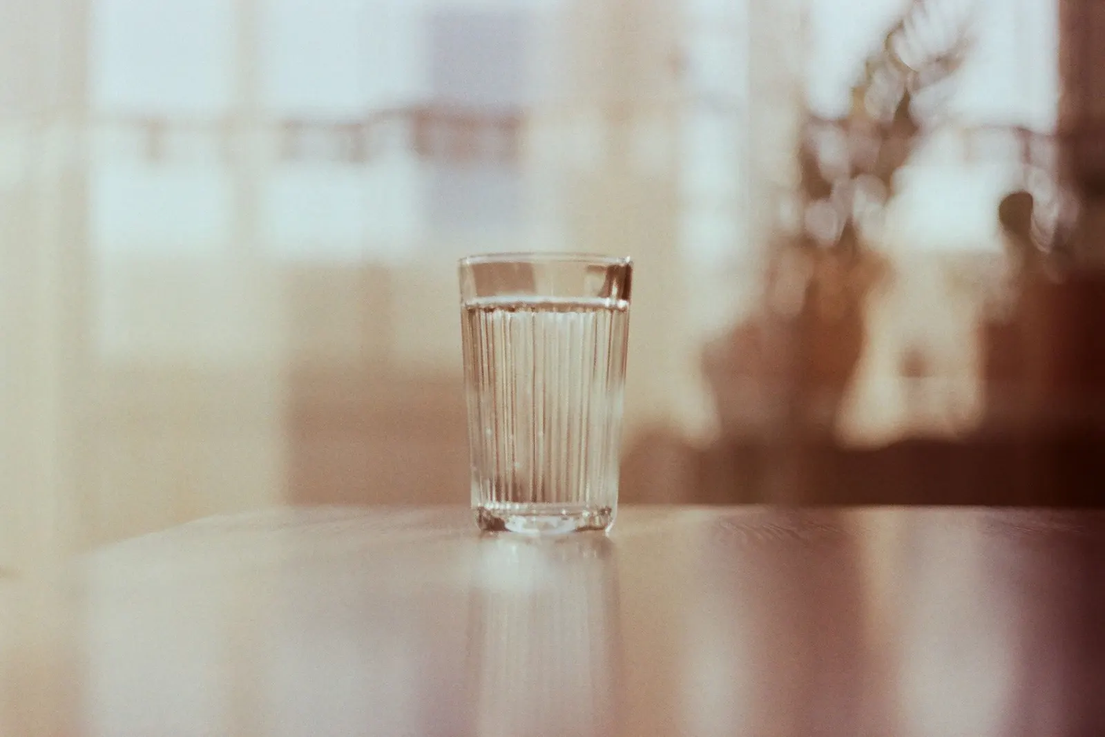 A woman filling a glass with water at the sink in a bright modern kitchen.