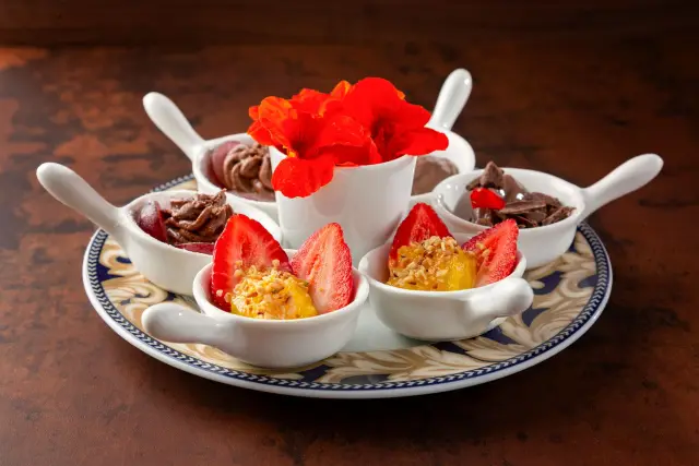 A dessert plate with strawberries and chocolate, plated after a meal.