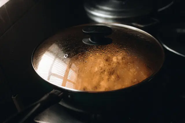 A steaming lidded pan on a stovetop in a home kitchen.